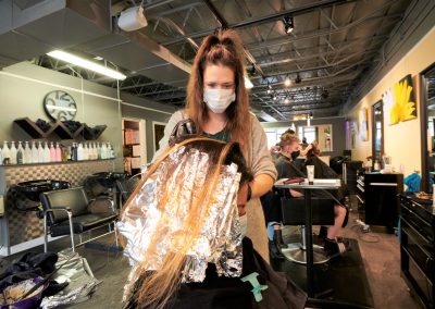 Hair stylist colouring the hair of female customer
